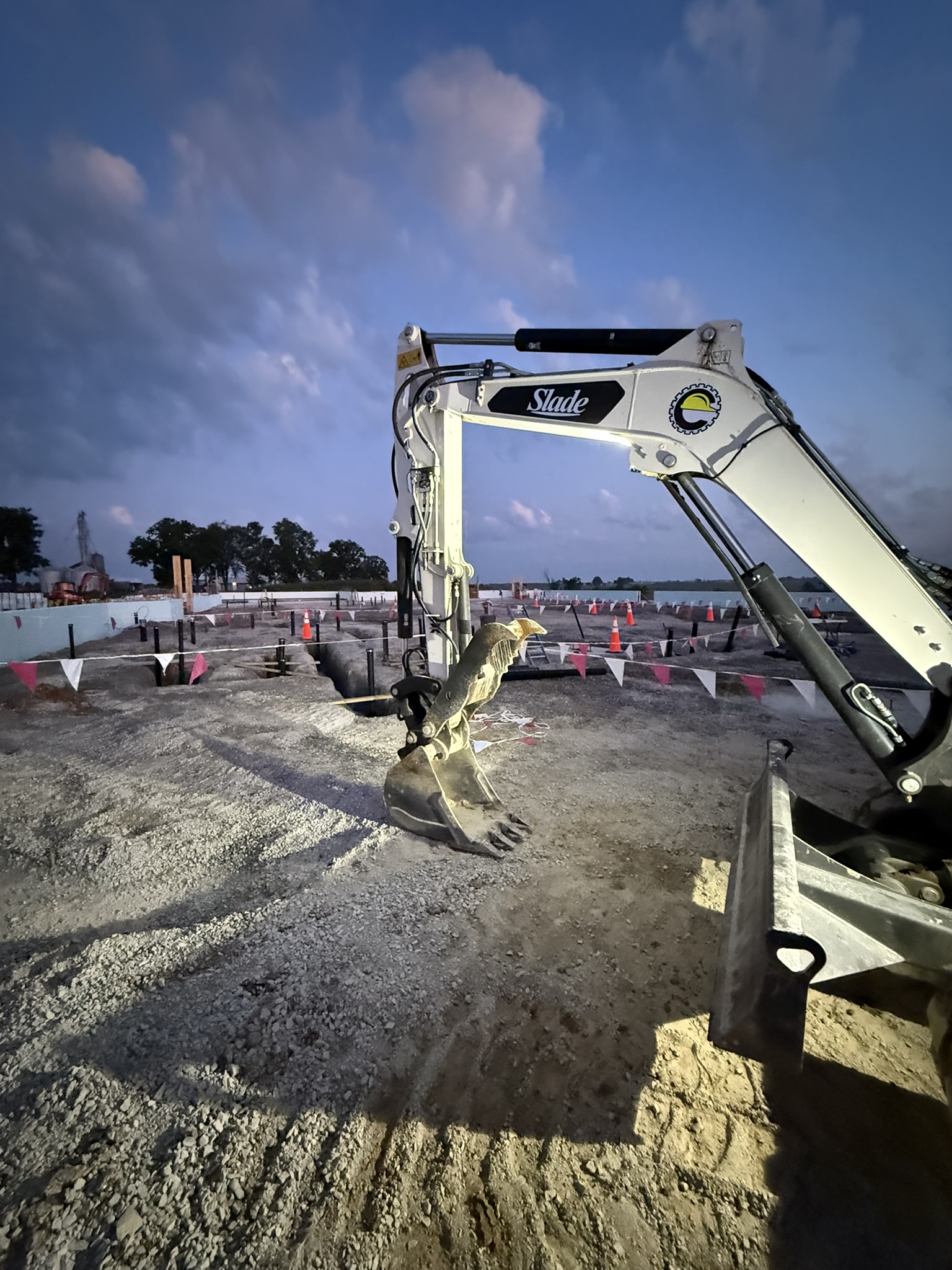 Excavator at dusk preparing building footers